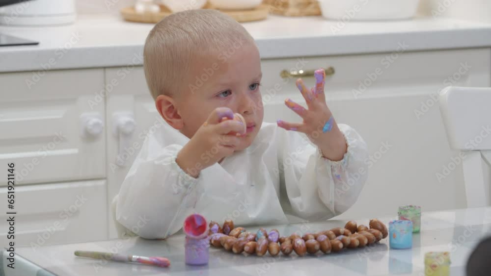 toddler child painting a necklace made of acorns with finger paints toddler child painting a necklace made of acorns with finger paints