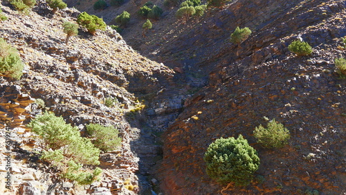 Vue au sommet de montagnes Atlas Maroc avec son environnement rocheux, jeu de lumière et d'ombre du Soleil, avec de la végétation, environnement désertique, effort physique intense, plus moins chemin photo