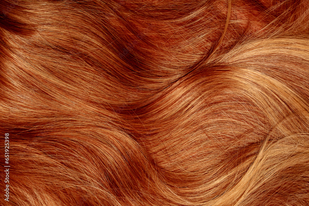 Fototapeta premium Red hair close-up as a background. Women's long orange hair. Beautifully styled wavy shiny curls. Hair coloring bright shades. Hairdressing procedures, extension.