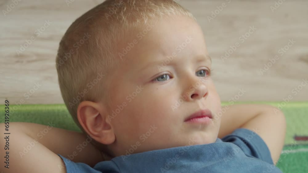 child is lying on the floor with his hands behind his head, little boy watching TV child is lying on the floor with his hands behind his head, little boy watching TV