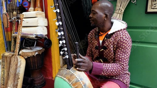 A Senegalese man plays a traditional kora string instrument. Traditional Afro-African music often played in the streets, at weddings, and at festivals. 4k footage. photo
