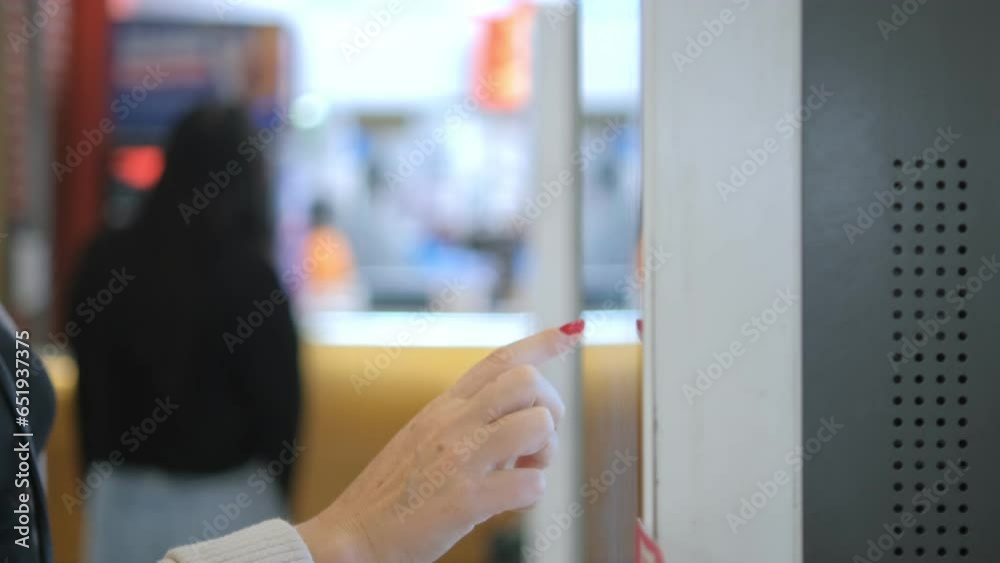 Girl using touch terminal makes a quick order through the self-service. Woman choosing dessert via self-service machine at fast food restaurant. Person swipes the screen making an order. Girl using touch terminal makes a quick order through the self-service. Woman choosing dessert via self-service machine at fast food restaurant. Person swipes the screen making an order.