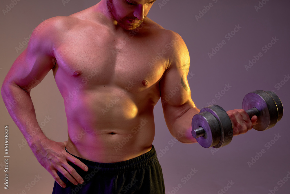 sporty well-built man with dumbbell in hand, guy takes part in challenge, changing body process, isolated brown background, cropped shot, focus on strong perfect body