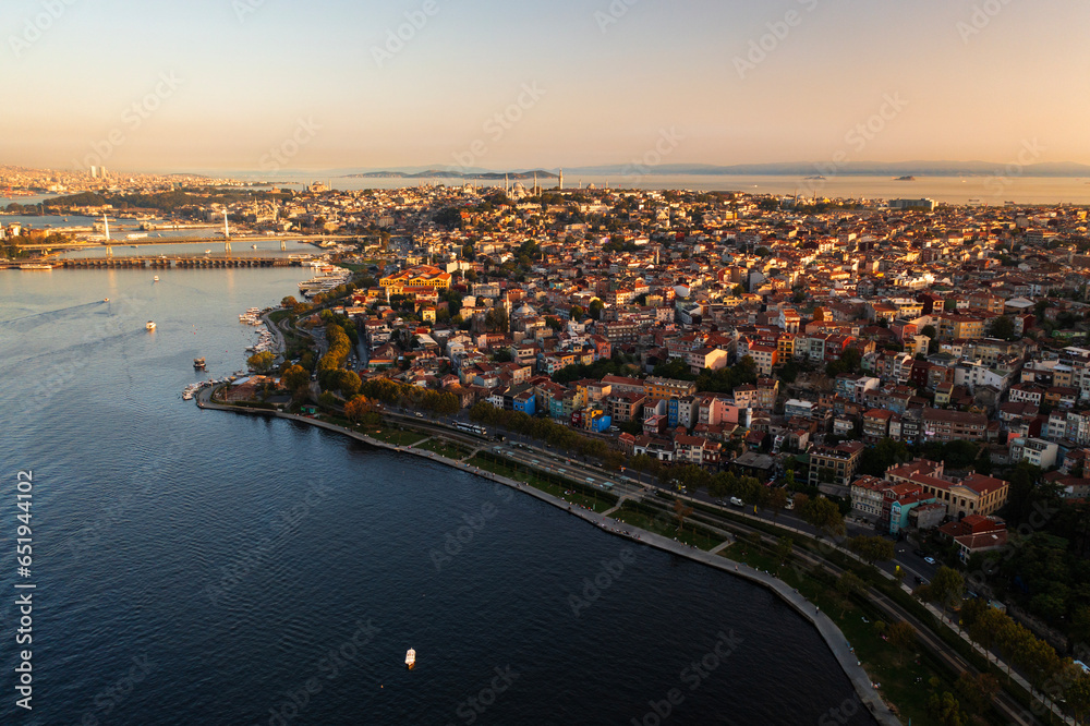 Aerial drone view of Istanbul, Turkey. Halic Bridge with multiple moving cars, multiple residential buildings on the both sides of the Golden Horn waterway, greenery, downtown on the background