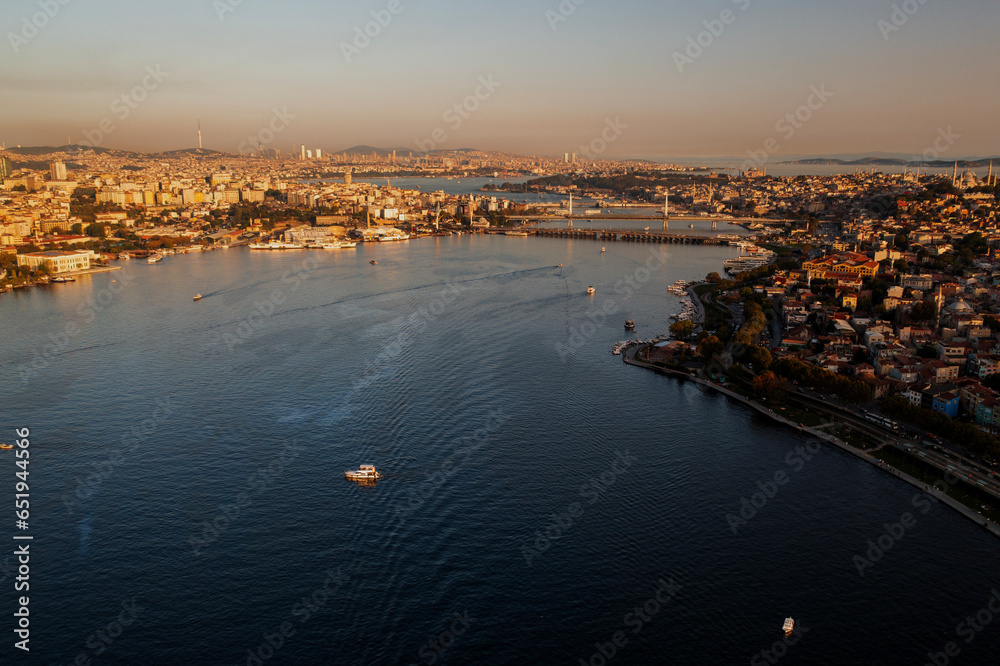 Aerial drone view of Istanbul, Turkey. Halic Bridge with multiple moving cars, multiple residential buildings on the both sides of the Golden Horn waterway, greenery, downtown on the background