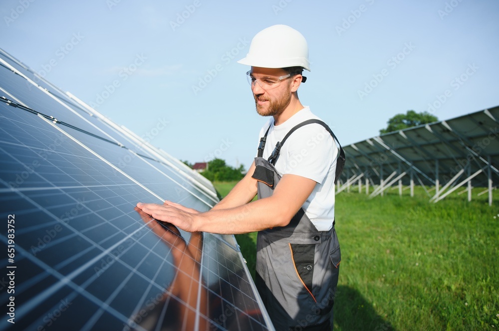 Male worker solar power plant on a background of photovoltaic panels.