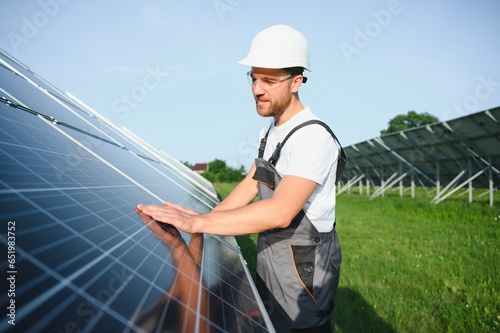 Male worker solar power plant on a background of photovoltaic panels.