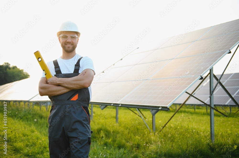 Male worker solar power plant on a background of photovoltaic panels.