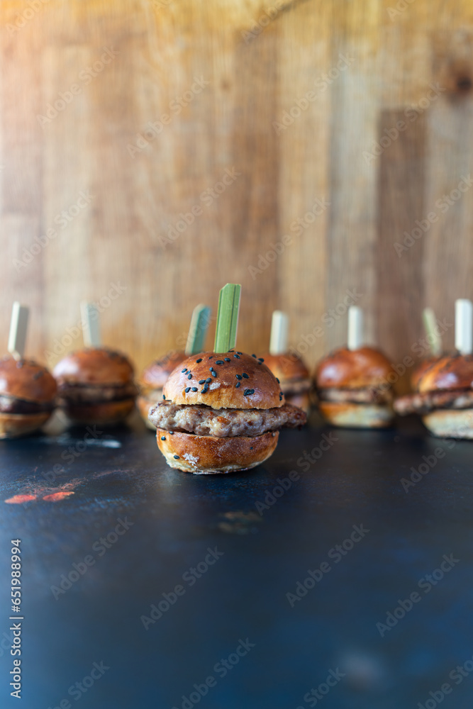 Close-up of mini burgers with a wooden toothpick ready for a party snack.Front view