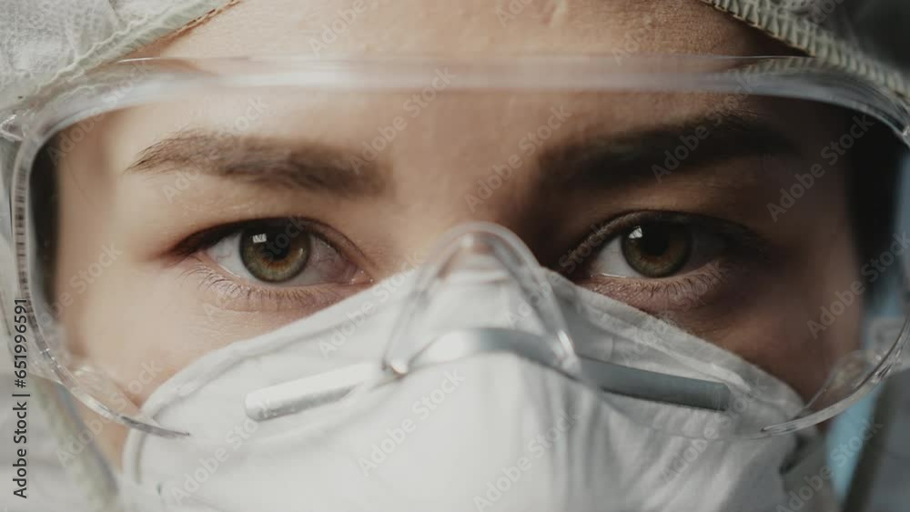 Medical Hospital Closeup Portrait: Seroius asian face in protective mask and glasses, eyes looking at camera. Female Doctor zoom out. Care Physician in White Lab Coat. Health care, medicine concept Medical Hospital Closeup Portrait: Seroius asian face in protective mask and glasses, eyes looking at camera. Female Doctor zoom out. Care Physician in White Lab Coat. Health care, medicine concept