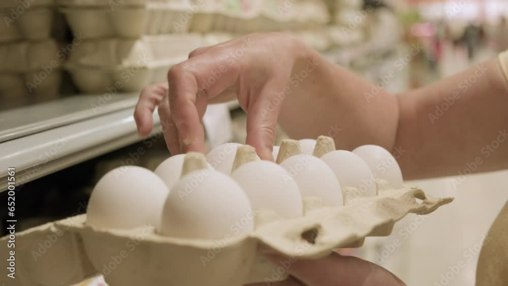 Woman inspects chicken eggs in box in supermarket for shell damage before buying. Woman inspects chicken eggs in box in supermarket for shell damage before buying.