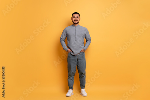 Smiling Young Asian Man Wearing Stylish Eyeglasses Posing Over Blue Studio Background