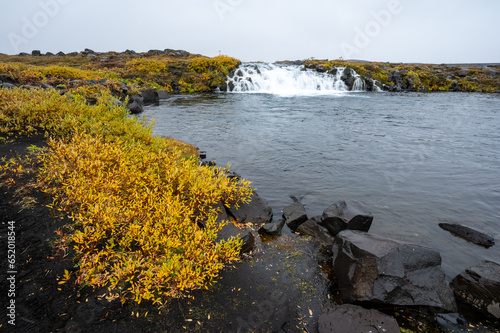 Grafarlandsfoss falls amidst colorful autumn vegetation and black lava fields on road F88 in highlands of northern Iceland. photo