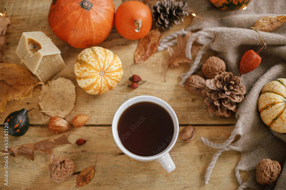 Warm cup of tea, pumpkins, fall leaves, candle, cozy scarf on rustic wooden table flat lay. Hygge autumn banner. Happy Thanksgiving. Fall still life