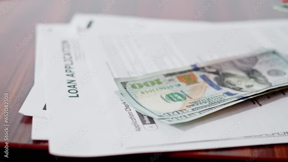 Loan application form with dollar cash money on it. Concept of taking a loan for a renting house or buying it. Loan application form with dollar cash money on it. Concept of taking a loan for a renting house or buying it.
