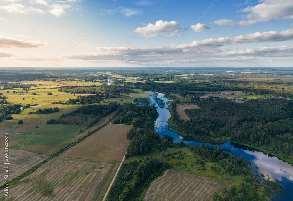 Fototapeta premium Aerial view over fields, forest and river in sunny summer day. Landscape.