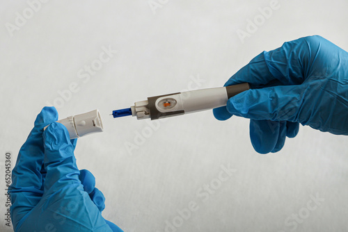 Medicine, diabetes, blood glucose, health care and people concept - Foreground a doctor preparing to use the lancet on his finger to check high blood sugar level with glucometer or glucometer at home. photo