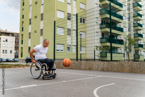 Foto A man in a wheelchair practices free throws on a street basketball court