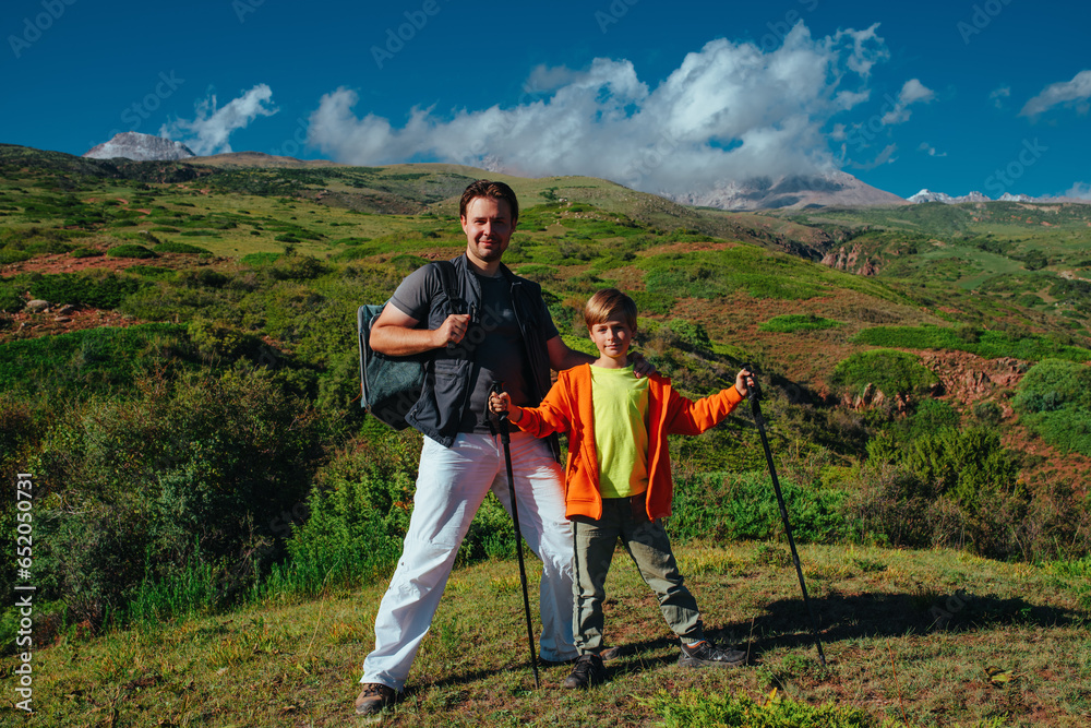 Happy father and son hikers standing on the mountain
