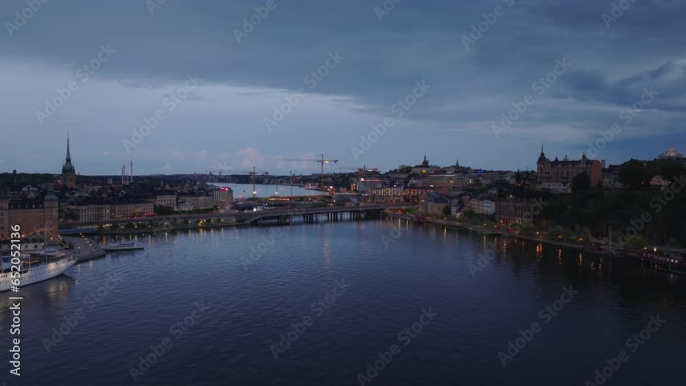 Aerial view of bridges over water in city and tower cranes on construction site in background. Fly over watercourse in evening. Stockholm, Sweden Aerial view of bridges over water in city and tower cranes on construction site in background. Fly over watercourse in evening. Stockholm, Sweden