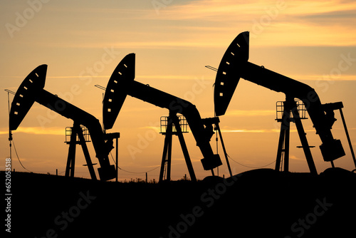 Oil and gas pump jack silhouette on the Canadian prairies in Rocky View County Alberta Canada photo