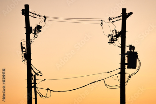 Power pole silhouette of transmission lines at sunset In Alberta Canada.