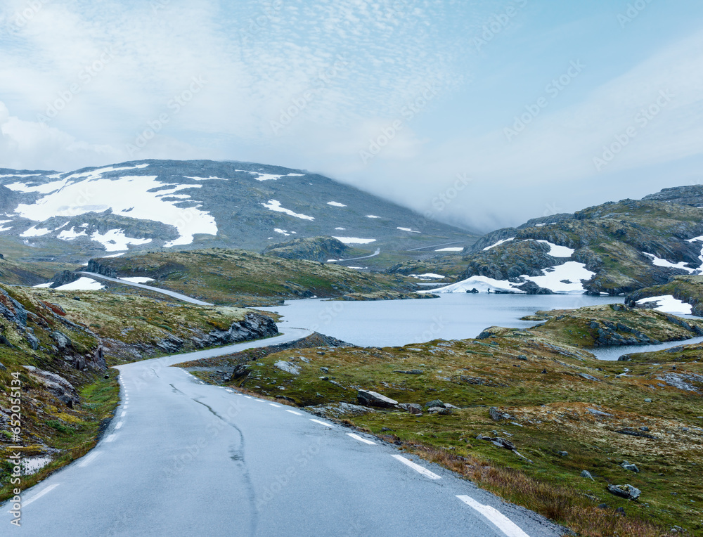 Summer mountain misty landscape with road, lake and snow (Norway, Aurlandsfjellet).