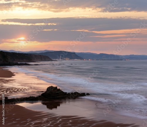 Twilight ocean rocky coast landscape with sky reflection on wet sand of beach  Spain .