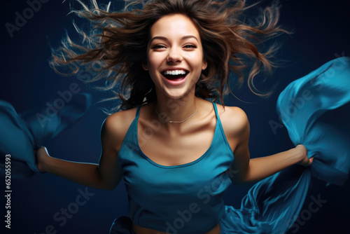 Woman wearing blue top is captured mid-air, appearing to be flying. This image can be used to depict freedom, joy, and empowerment.
