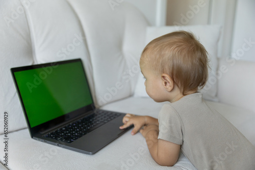 A little boy works on a laptop, presses buttons in a room at home. A small programmer, the concept of early development and online education.