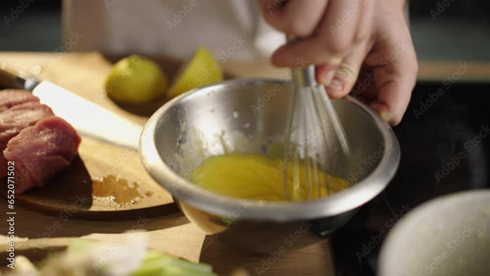 Slow-motion shot of a chef mixing egg yolks with a kitchen whisk in the home kitchen Slow-motion shot of a chef mixing egg yolks with a kitchen whisk in the home kitchen