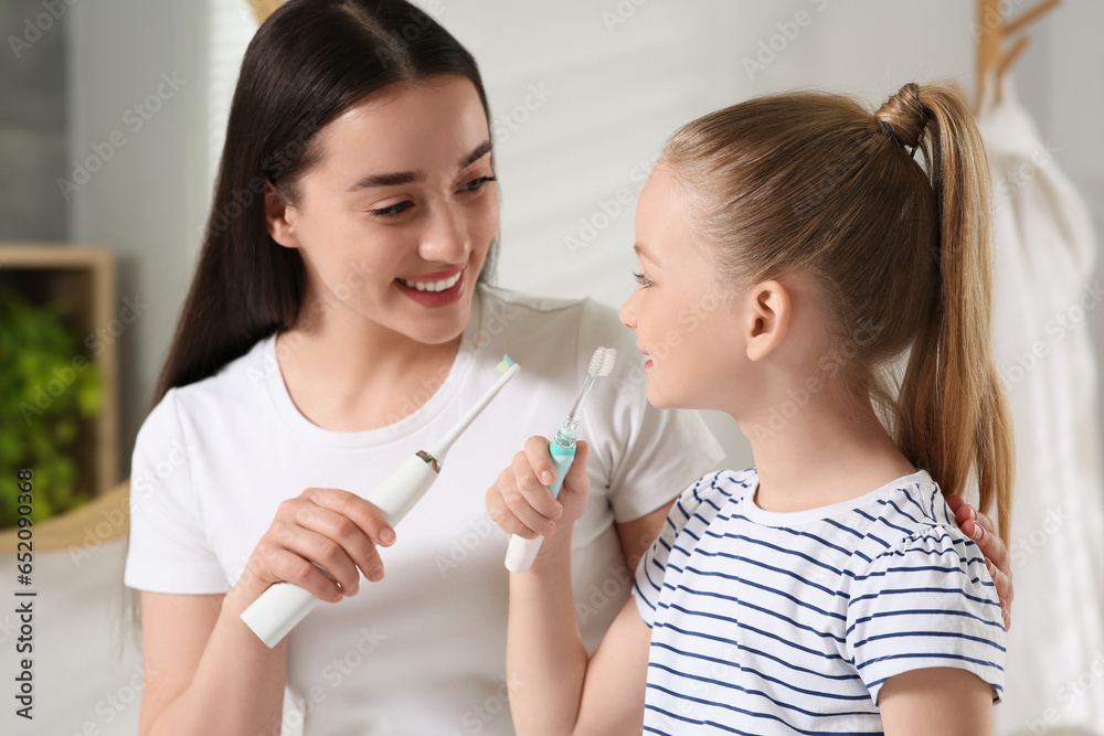 Mother and her daughter brushing teeth together in bathroom Mother and her daughter brushing teeth together in bathroom