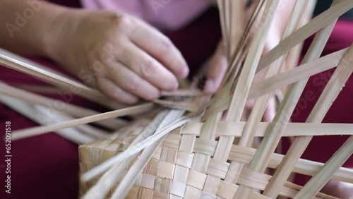 An Indonesian woman´s hand weaving an ancestral basket case from mangrove palm leaves . People is demonstrating weaving basket made from nipa palm. Weaving a traditional basket made from mangrove palm