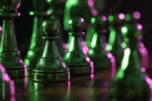 Chess pieces on checkerboard in color light, selective focus