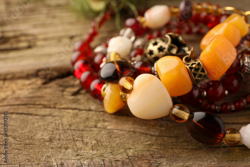 Beautiful bracelets with gemstones on wooden surface, closeup, Space for text