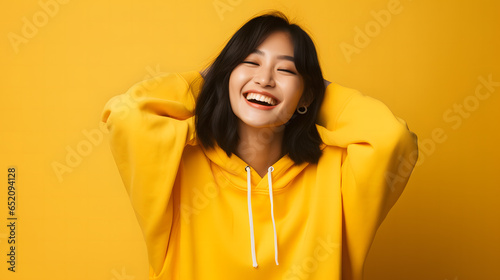 Elegant T-Shirt Mockup: Asian Woman in Bella Canvas White Shirt, Smiling Against a Yellow Background © Rodrigo