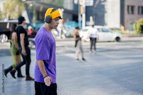 Dancing latino young man with headphones listening to music performing various freestyle dance outdoors having fun. hiphop dancing, street dancing