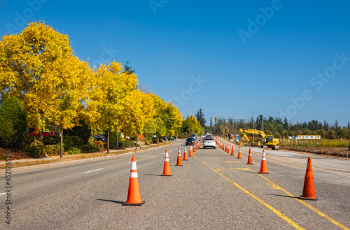 Traffic sign with flags reading Utilitary Work Ahead with traffic cones on road. Row of Traffic cone in the road repair photo