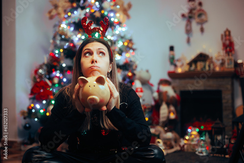Broke Woman Holding a Piggy Bank Regretting Christmas Spendings. Desperate girl feeling sad about spending too much money on holidays