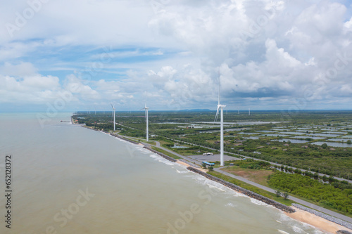 Aerial view of wind turbines or windmills farm field and sea shore beach in industry factory. water power, sustainable green clean energy, and environment concept. Nature innovation. © tampatra