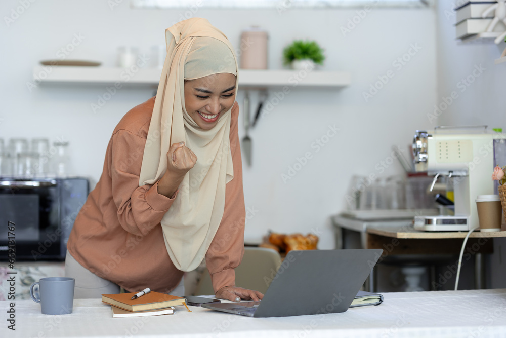 Surprised and happy businesswoman raises her arms to express joy after viewing and knowing business approval and financial approval results on laptop at home office. startup business growth ideas Surprised and happy businesswoman raises her arms to express joy after viewing and knowing business approval and financial approval results on laptop at home office. startup business growth ideas