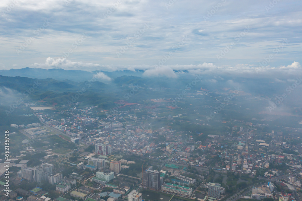 Obraz premium Aerial view of residential neighborhood roofs with fog mist in rainy season. Urban housing development from above. Top view. Real estate in Phuket, southern province city, Thailand.