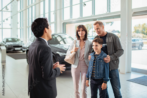 Young caucasian family talking to a car salesman in a car dealership