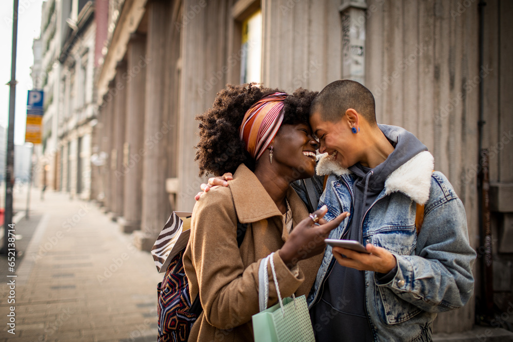 Young interracial lesbian couple shopping and using a phone in the city Young interracial lesbian couple shopping and using a phone in the city