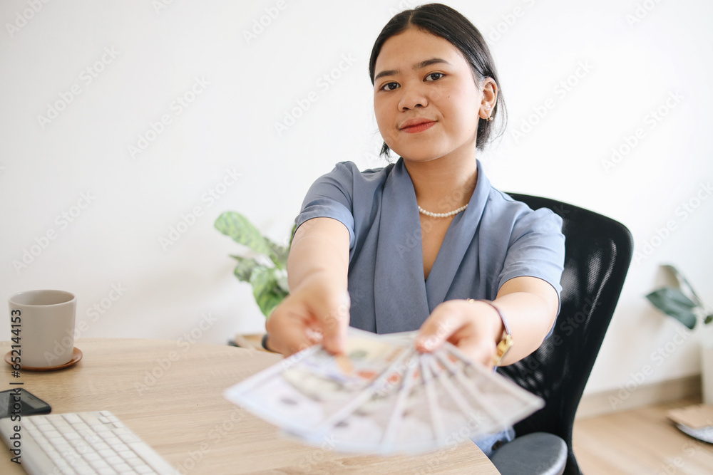 Successful young Asian businesswoman showing earned cash, smiling as holding dollars Successful young Asian businesswoman showing earned cash, smiling as holding dollars
