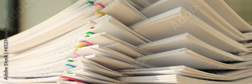 High stack of office documents with clips on office table close up.