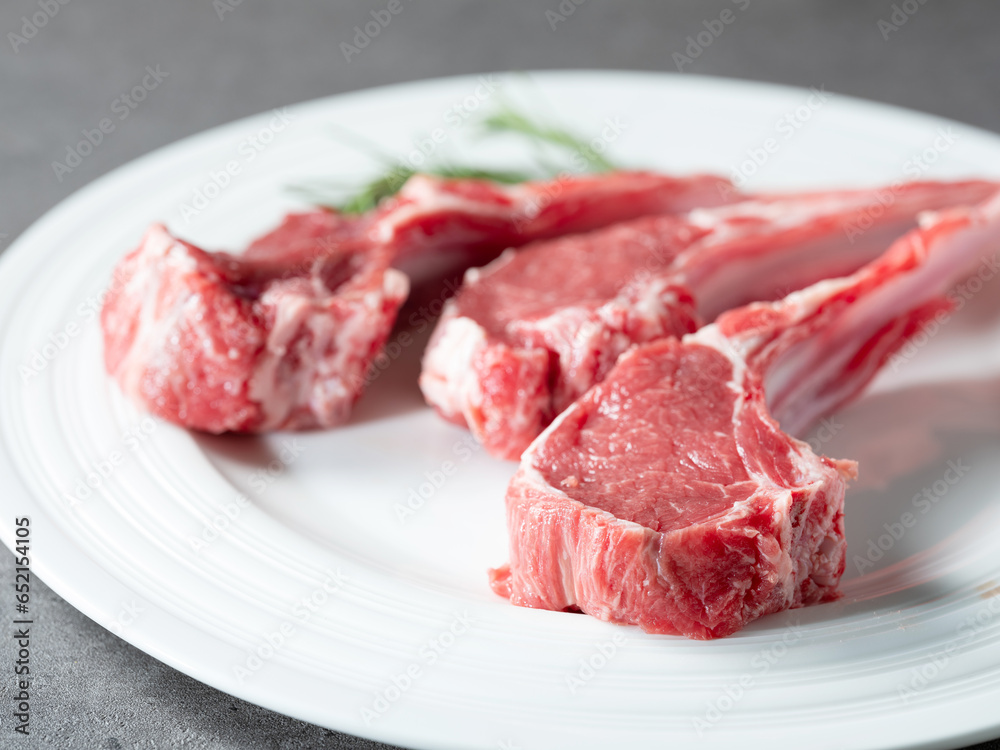 Raw lamb ribs with rosemary on a plate