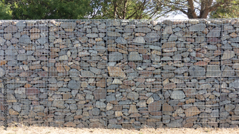 Fototapeta premium stone textured fence gabion steel metal grated stone wall basket made of mesh and stones background wall horizontal facade