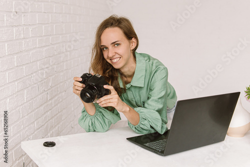Smiling young woman with camera and a laptop. Photo processing. Natural. Woman photographer