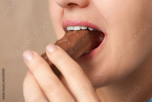 Close up of mouth of happy Caucasian woman eating chocolate bar. Three-quarter front view. Low angle view.